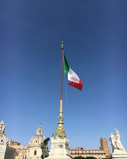 Low angle view of flag on building against clear blue sky