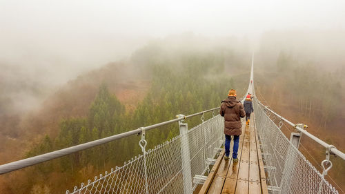 Rear view of man working on footbridge in foggy weather