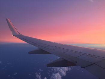 Airplane wing against sky during sunset