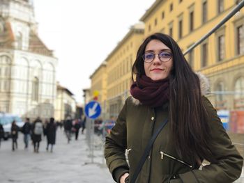 Portrait of smiling young woman standing in city during winter