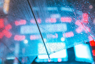 Close-up of raindrops on transparent umbrella at night