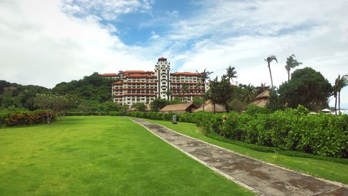 Lawn by building in park against sky