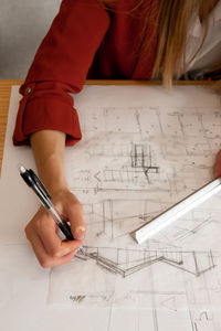Close up of woman wearing orange outfit while drawing architecture sketches in office