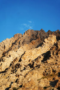 Low angle view of rock formations against clear blue sky