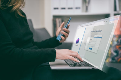 Midsection of woman using laptop on table
