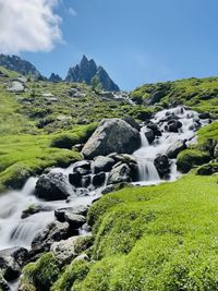 Scenic view of stream flowing amidst rocks against sky