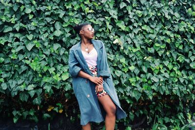 Young woman standing by plant