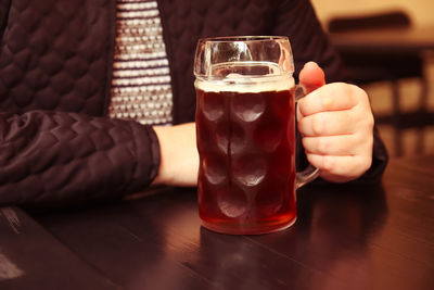 Close-up of hand holding drink on table