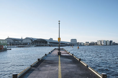 Street by river against buildings in city against sky