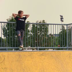 Full length of man jumping on railing against sky