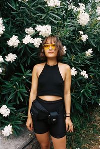 Beautiful young woman standing by flower plants