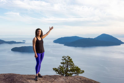 Full length of young woman standing on mountain against sky