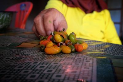 Close-up of person holding fruits on table