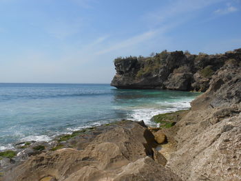 Rock formation on beach against sky