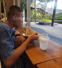 Rear view of boy drinking glass on table
