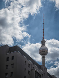 Low angle view of communication tower against cloudy sky