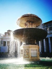 Fountain in front of built structure against clear sky