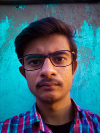 Portrait of young man wearing sunglasses against wall