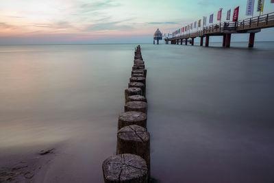 Pier over sea against sky during sunset