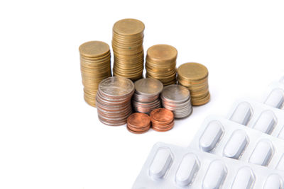 High angle view of coins and medicine on white background