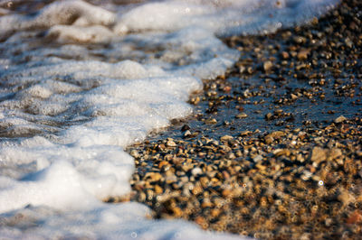 Sea waves crashing on a beach of colored stones