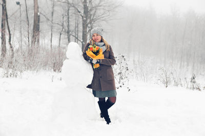 Full length of woman skiing on snow covered field