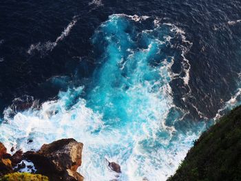 High angle view of waves splashing on rocks in sea