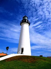 Low angle view of lighthouse by building against sky