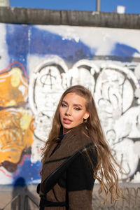 Woman standing against graffiti wall