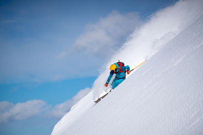 Man skiing on snowcapped mountain against sky