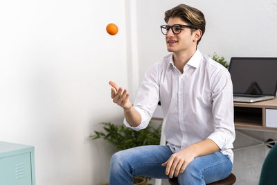 Full length of young man sitting on wall