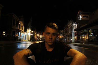 Portrait of young man on illuminated street at night