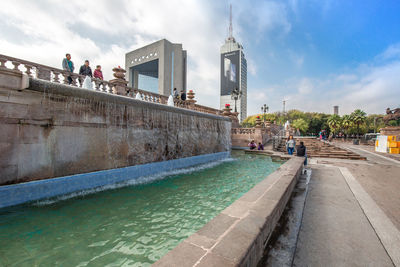 People in swimming pool against buildings in city