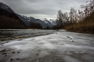 Scenic view of lake by snowcapped mountains against sky