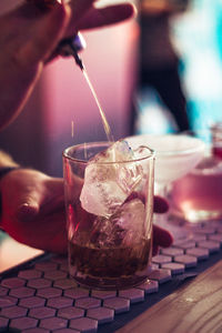 Close-up of hand pouring drink in glass on table