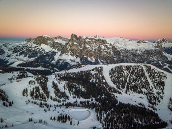 Snow covered landscape against sky during sunset