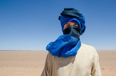 Portrait of man wearing headscarf at desert