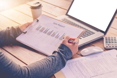 Cropped hands of woman holding chart at office