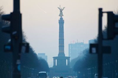 Statue in city against sky