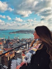 Woman looking at cityscape against sky