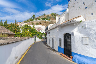 Road amidst houses against sky