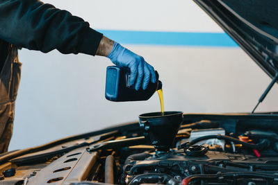 Cropped hand pouring oil in car engine