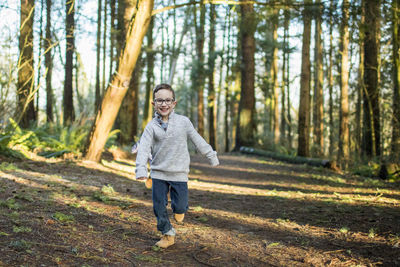 Young boy running through the forest.