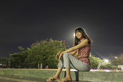 Young woman wearing hat against sky at night