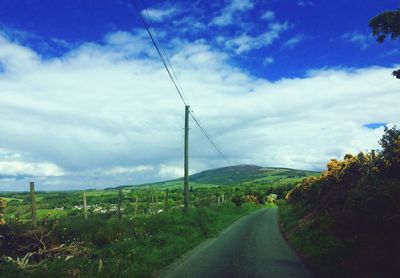 Road amidst green landscape against sky