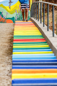 Low section of people walking on multi colored umbrella