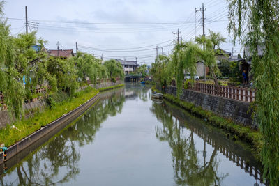 Canal amidst trees and buildings against sky