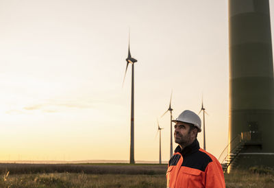 Male inspector wearing hardhat and reflective clothing at sunset