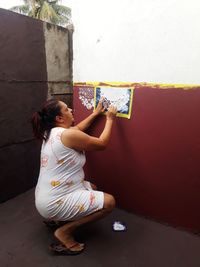 Side view of woman painting on wall