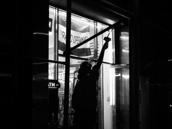 Rear view of silhouette woman standing against illuminated building at night